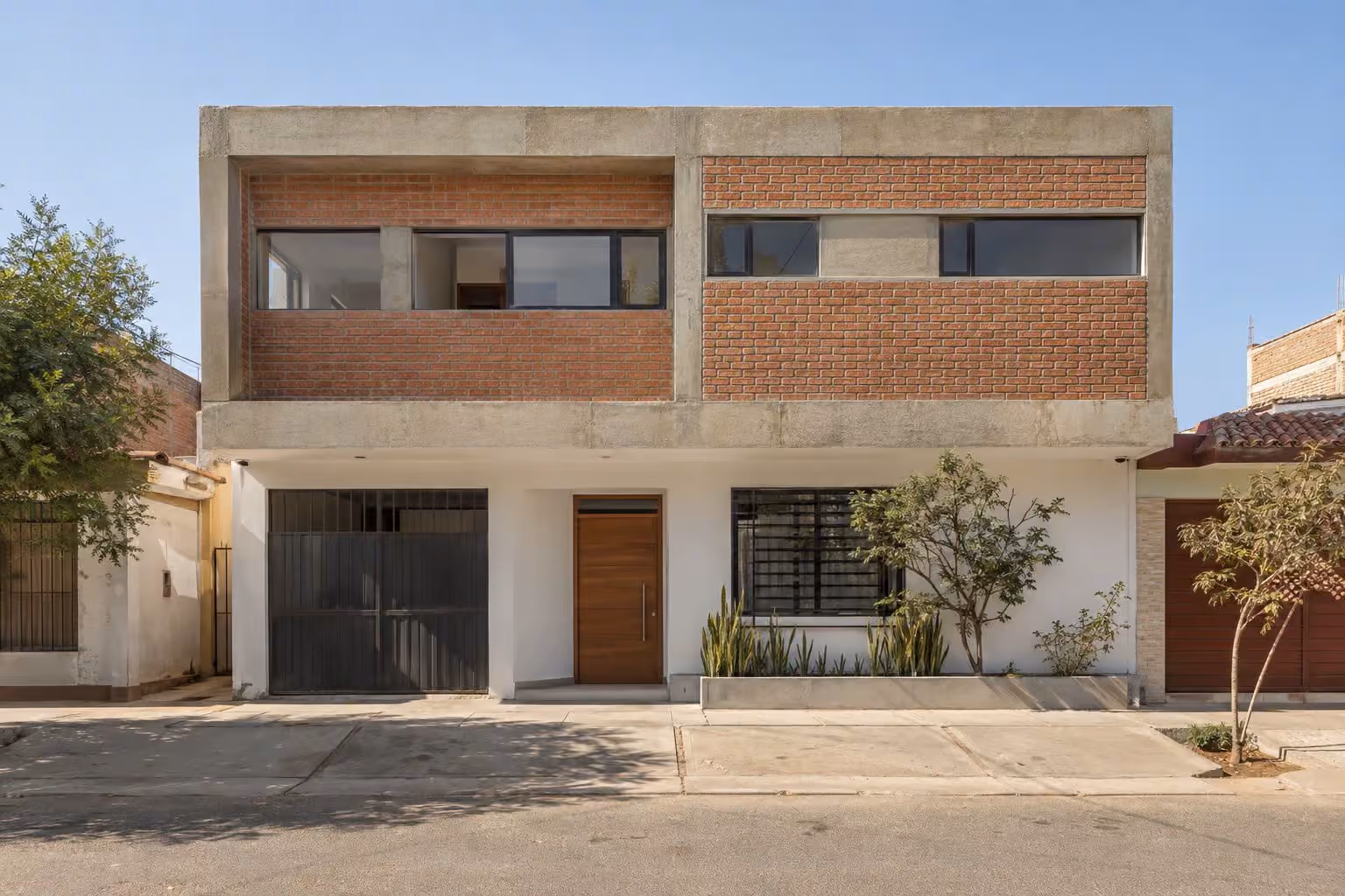 Casa de un piso con una ampliación nueva de concreto y ladrillo en el segundo nivel